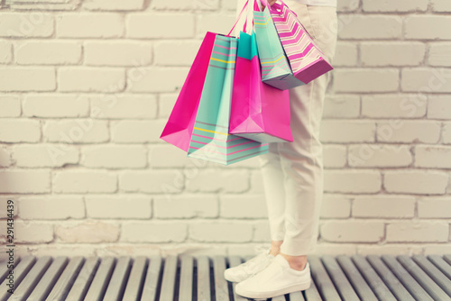 Stylish girl in white clothes holding pink shopping bags. Sale, discount, black friday concept. Shopping mall and outlet