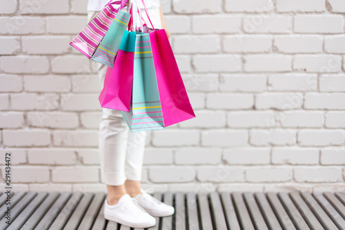 Shopping concept. Girl holding bunch of shopping bags with purchases near brick background. Copy space. Sale, discount, black friday concept. Shopping mall and outlet