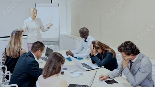 Unhappy business woman blaming subordinates for bad work on staff meeting at office