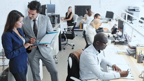 Male and female office workers in business suits having conversation in modern office