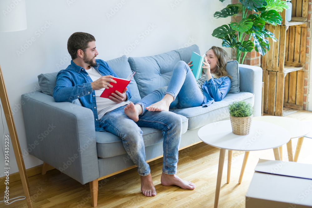 Young couple relaxing on the sofa reading a book, taking a break for moving to new house Young couple relaxing on the sofa reading a book, taking a break for moving to new house