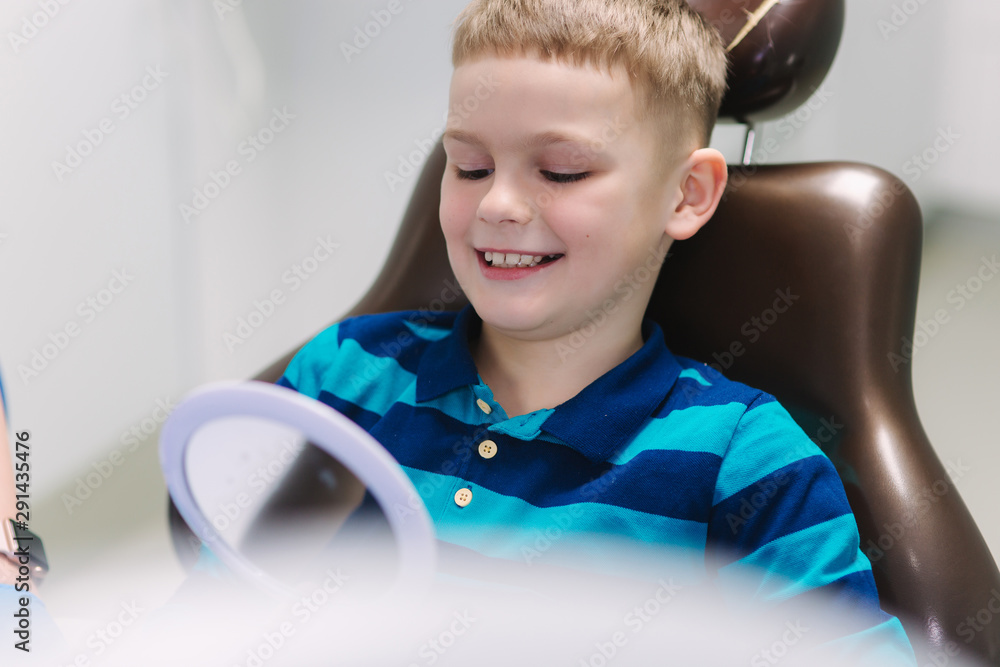 Little boy sitting in dantist chair with mirror. Male patient look at his teeth Little boy sitting in dantist chair with mirror. Male patient look at his teeth