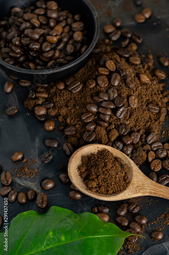 Wooden Spoon filled with coffee powder and coffee beans isolated on dark background