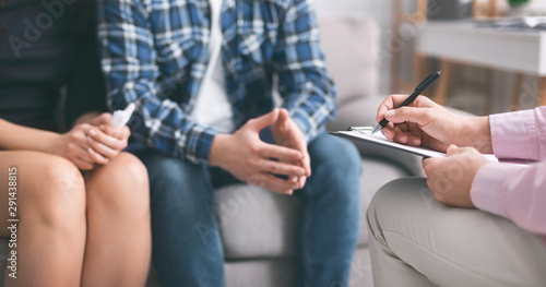 Therapist writing hometask for psychological work to young couple photo