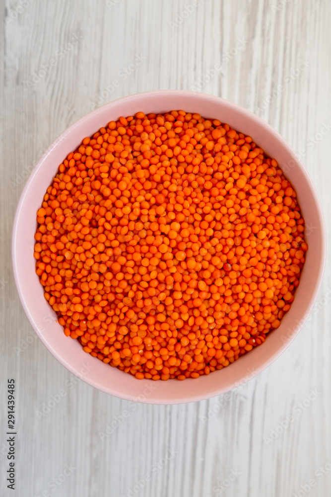 Red lentils in a pink bowl over white wooden background, top view. Flat lay, overhead, from above. Close-up. Red lentils in a pink bowl over white wooden background, top view. Flat lay, overhead, from above. Close-up.