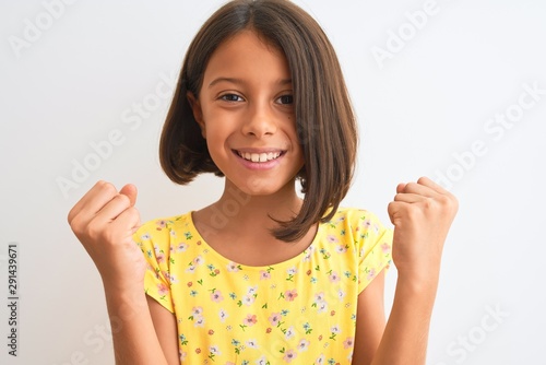 Young beautiful child girl wearing yellow floral dress standing over isolated white background screaming proud and celebrating victory and success very excited, cheering emotion