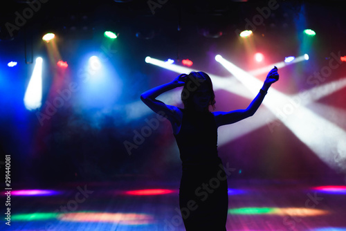 Silhouette of dancing girl against disco lights
