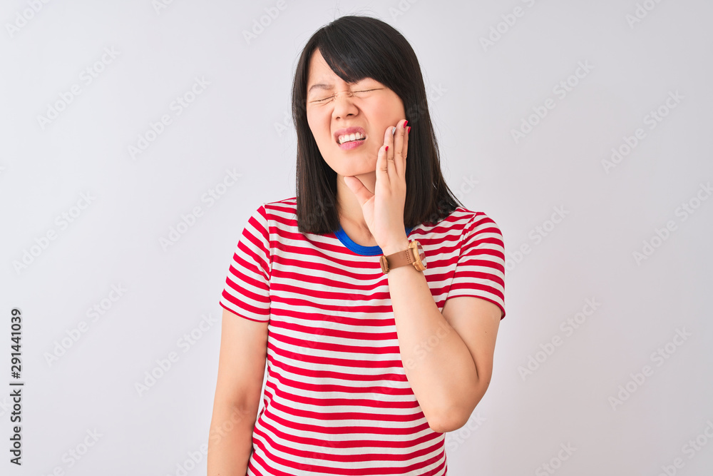 Young beautiful chinese woman wearing red striped t-shirt over isolated white background touching mouth with hand with painful expression because of toothache or dental illness on teeth Young beautiful chinese woman wearing red striped t-shirt over isolated white background touching mouth with hand with painful expression because of toothache or dental illness on teeth