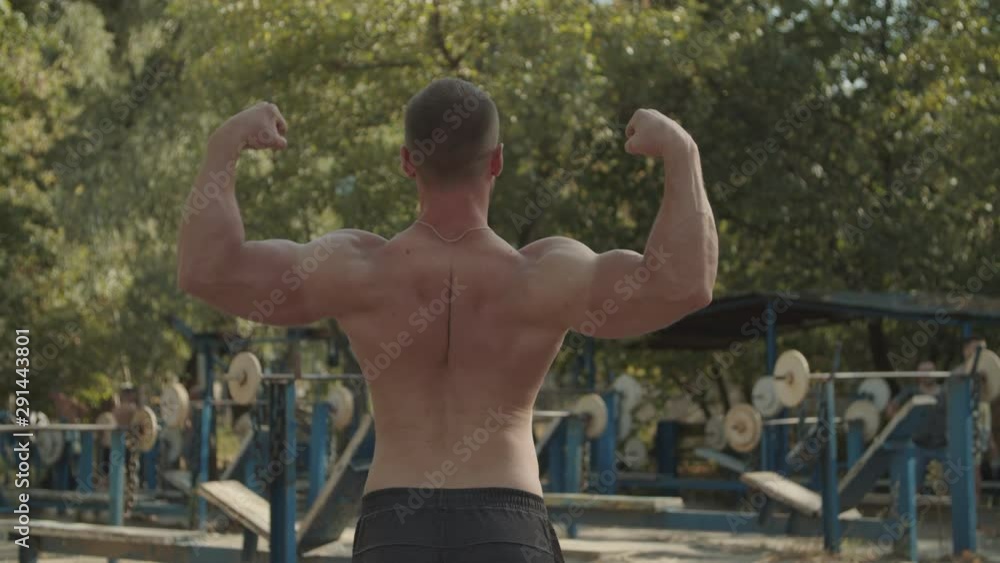 Rear view of shirtless strong bodybuilder with well trained six pack ...