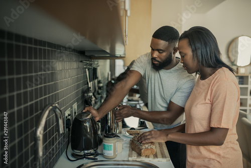 Fototapeta Naklejka Na Ścianę i Meble -  Young African American couple preparing breakfast in their kitchen