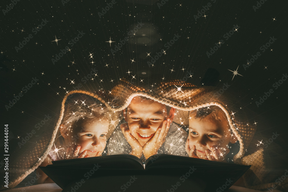 children reading a book under a blanket with light - obrazy, fototapety, plakaty 