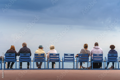 Couples sitting on the bank of the sea feeding pigeons and seagulls. © Sergey Bogomyako