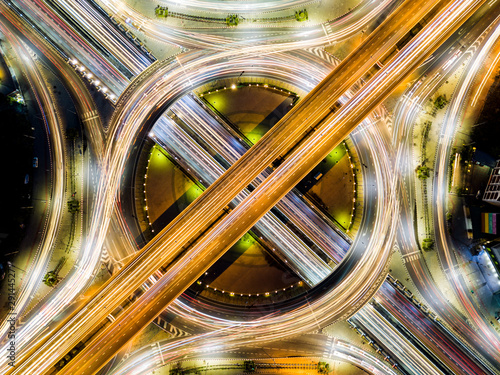 Beautiful roundabout intersection at night view. Aerial view of circle transportation in the city with colorful light. Drone view from night sky.