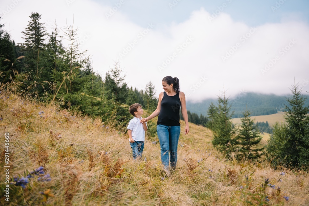 Naklejka premium Young mom with baby boy travelling. Mother on hiking adventure with child, family trip in mountains. National Park. Hike with children. Active summer holidays.