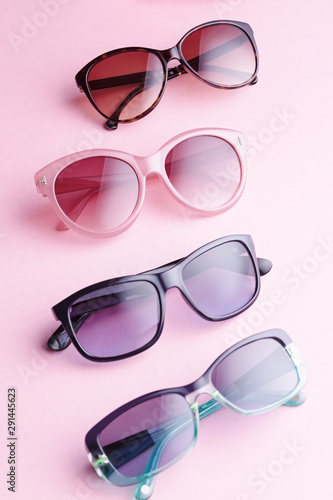 Collection of fashionable sunglasses on pink background. Sunglasses of different shapes and colors flat lay