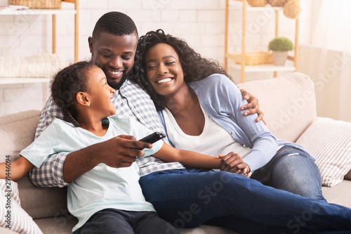 Happy african american family relaxing and watching TV at home photo