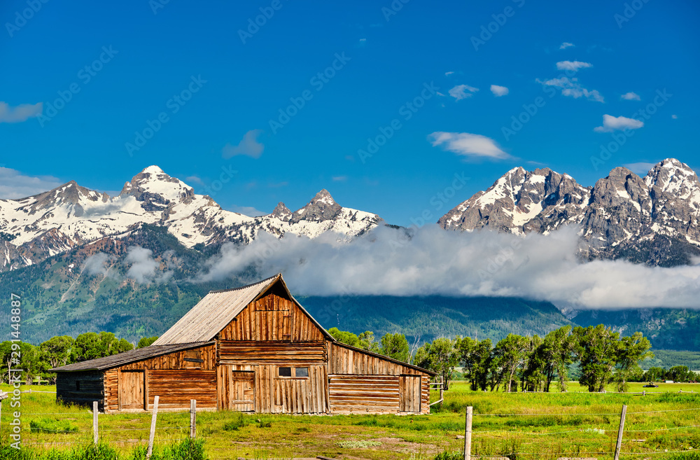 Old mormon barn in Grand Teton Mountains with low clouds. Grand Teton National Park, Wyoming, USA. Old mormon barn in Grand Teton Mountains with low clouds. Grand Teton National Park, Wyoming, USA.