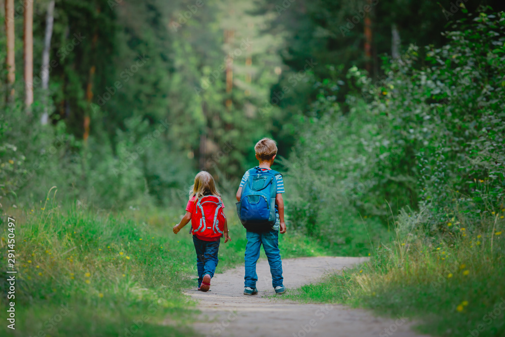 little boy and girl with backpacks going to school, kids walk in nature little boy and girl with backpacks going to school, kids walk in nature