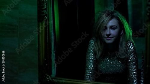 Tableau sur toile Woman looking in mirror, euphoria after snorting cocaine in night club toilet