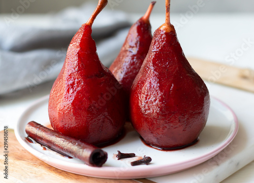 Red wine poached pears in white plate, delicious french dessert, close-up