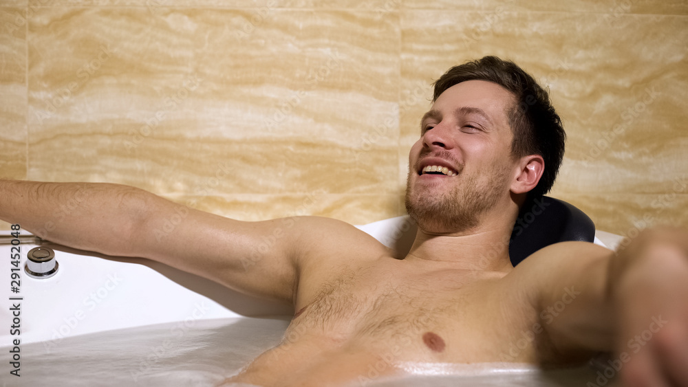 Funny man having fun taking bath, spending time resting and relaxing, home spa