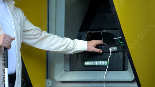 Quadro em tela Visually impaired man inserting password on atm machine, withdrawing money