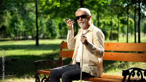 Visually impaired old man using voice control app in smartphone, innovations