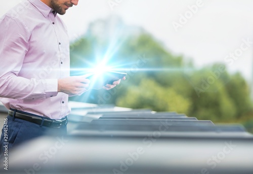 Attractive business man using digital tablet in balcony with green trees in background