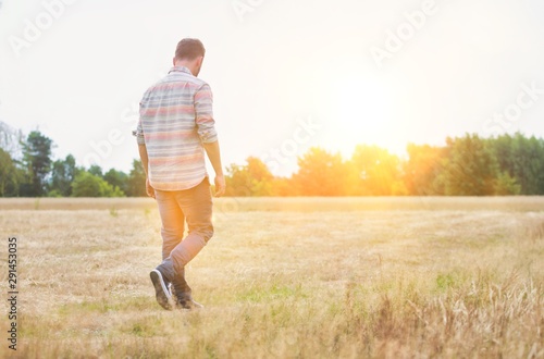 Rear view of Man walking alone in field