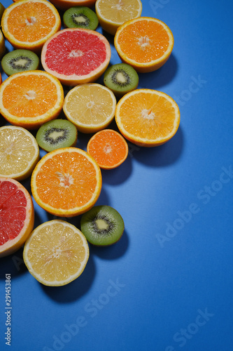 Fresh summer fruits on blue background. Flat lay. Tropical summer mix grapefruit, orange, mandarin, kiwi, lemon. Fruit background with copy space. © Oleg Samoylov