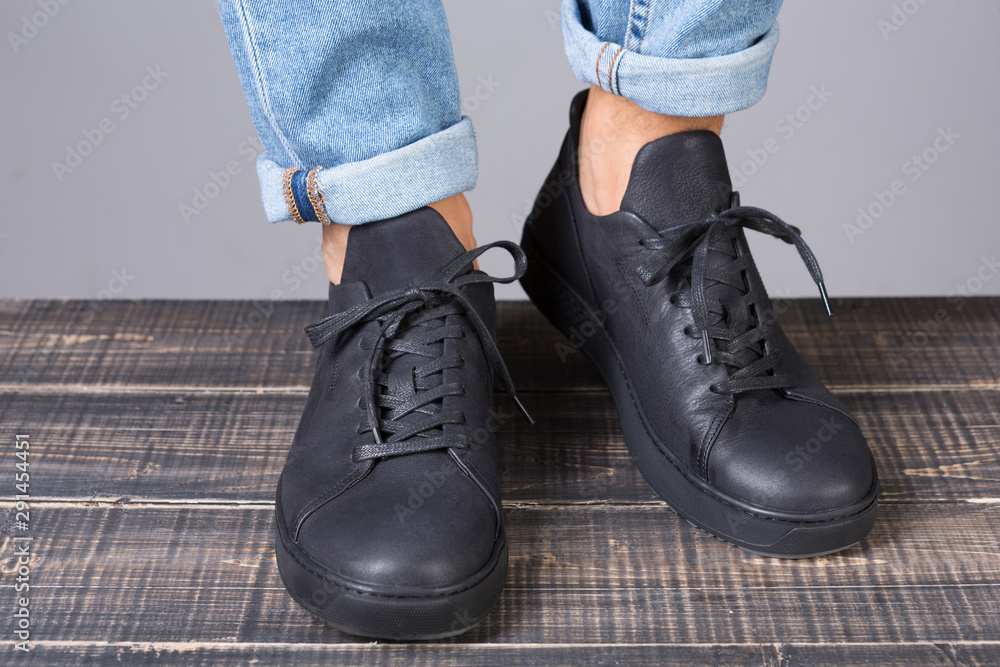 black leather shoes on male legs, on wooden boards, concept