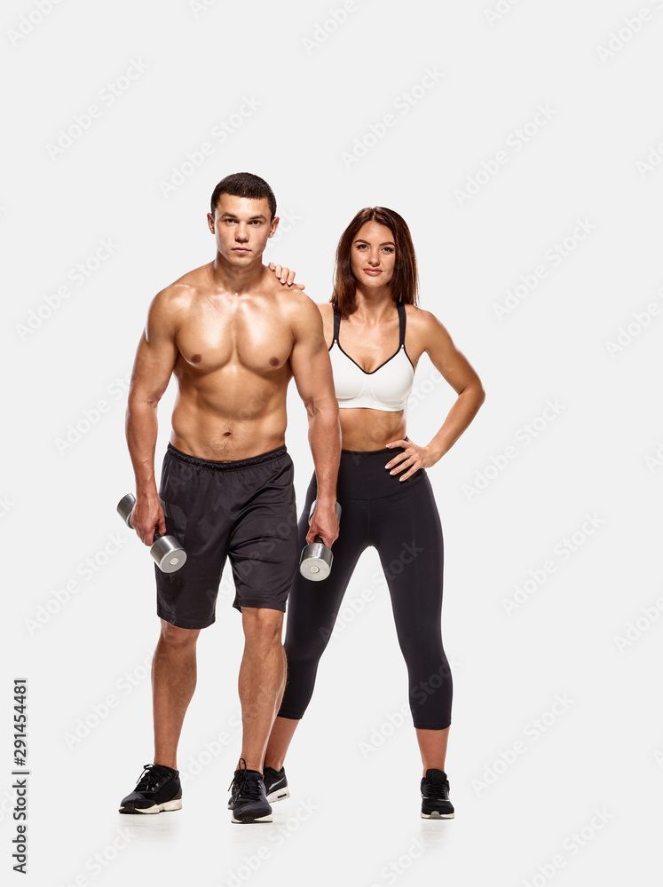 Portrait of strong healthy man and woman posing with dumbbells Portrait of strong healthy man and woman posing with dumbbells