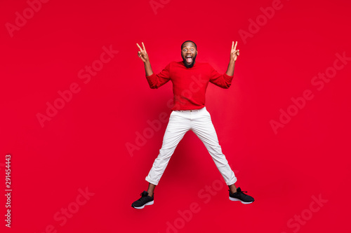 Full body photo of excited guy student jumping making v-signs wearing sweater pants trousers isolated over red background