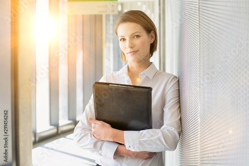 Young businesswoman holding leather document with yellow lens lare in background photo