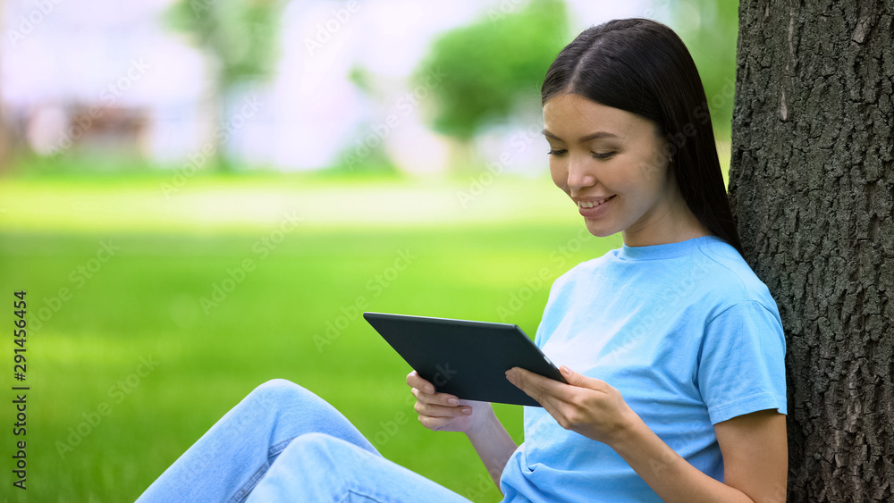 Attractive young woman watching tablet video sitting park, online application Attractive young woman watching tablet video sitting park, online application