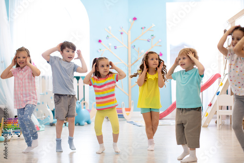 Happy kids having fun dancing indoors in a sunny room at day care or entertainment center
