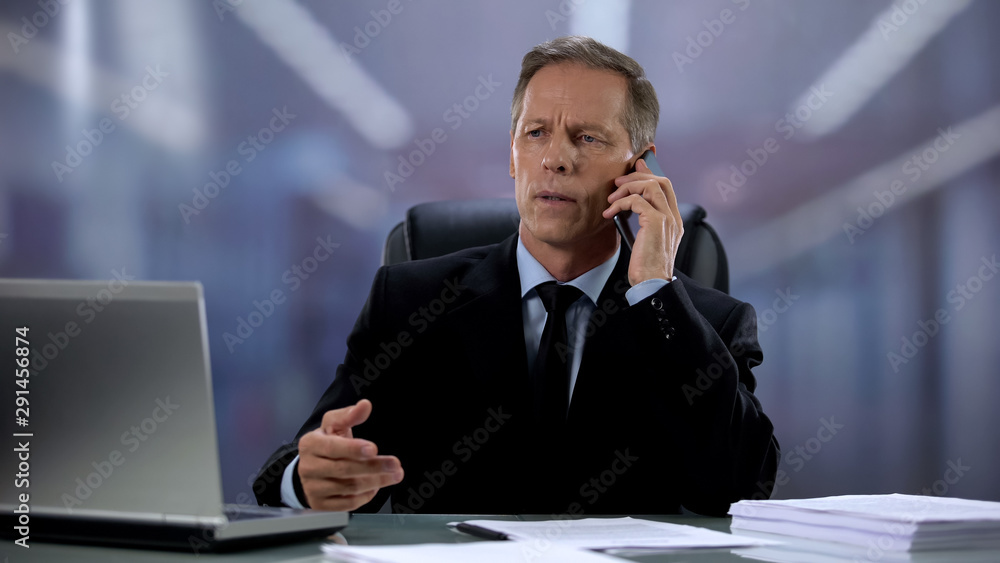 Serious businessman talking on phone with business partner, setting meeting Serious businessman talking on phone with business partner, setting meeting