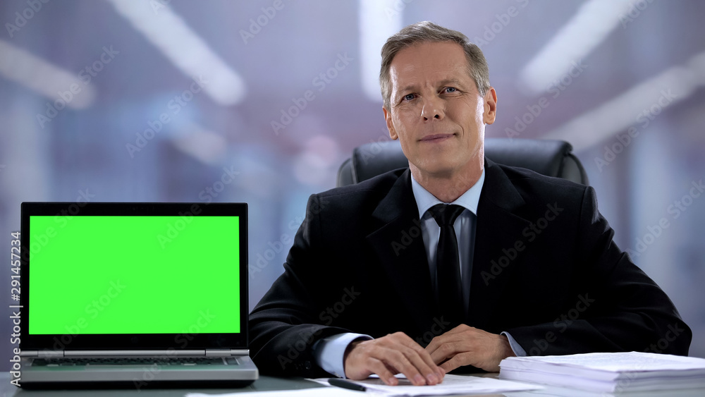 Business man smiling by laptop with green screen, presenting financial app Business man smiling by laptop with green screen, presenting financial app