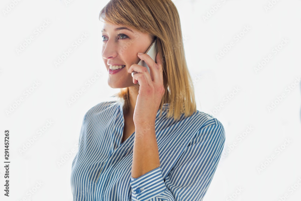 Smiling businesswoman talking on smartphone in office Smiling businesswoman talking on smartphone in office