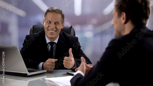 Friendly boss showing thumbs-up to candidate on interview, supporting employee