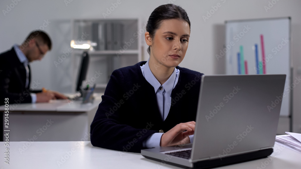 Tired female office worker typing on laptop, overworking concept, exhaustion Tired female office worker typing on laptop, overworking concept, exhaustion