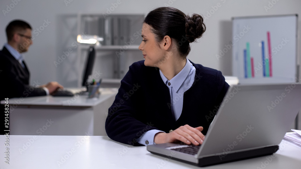 Cute female manager working on laptop, looking at male colleague, secret love Cute female manager working on laptop, looking at male colleague, secret love