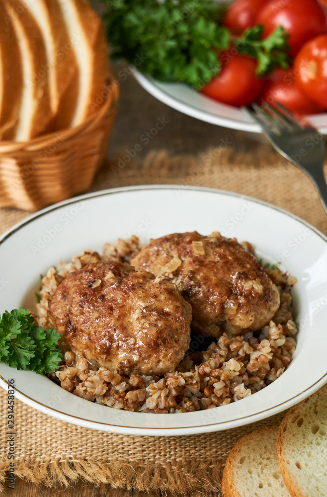 Fried meat cutlets with buckwheat in a white bowl