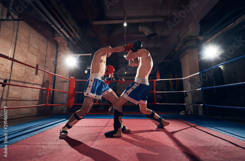 Two professional boxers training kickboxing in the ring at the health club