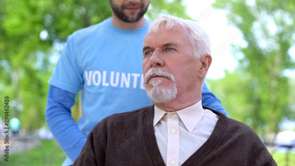 Male volunteer spending time with elderly nursing home patient, outdoors
