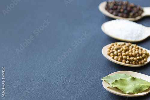 composition of assorted spices in wooden spoons on a dark background. bay leaf in the front. close up