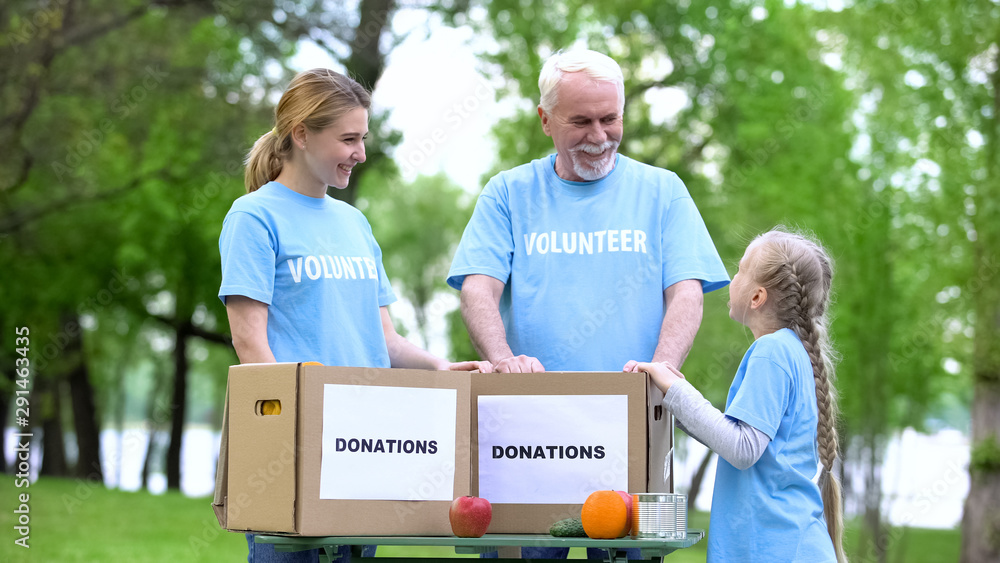 Naklejka premium Child volunteer talking to family, fruits and canned food with donation boxes