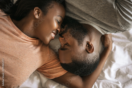 Loving young African American couple lying in bed together