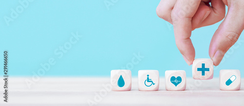 Fototapeta Naklejka Na Ścianę i Meble - Hand chooses a emoticon icons healthcare medical symbol on wooden block , Healthcare and medical Insurance concept