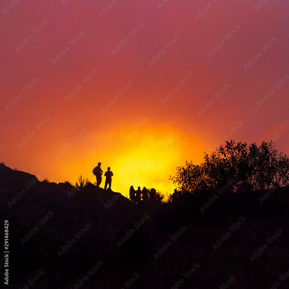 A group of people meet the sunrise at the peak of the mountain.